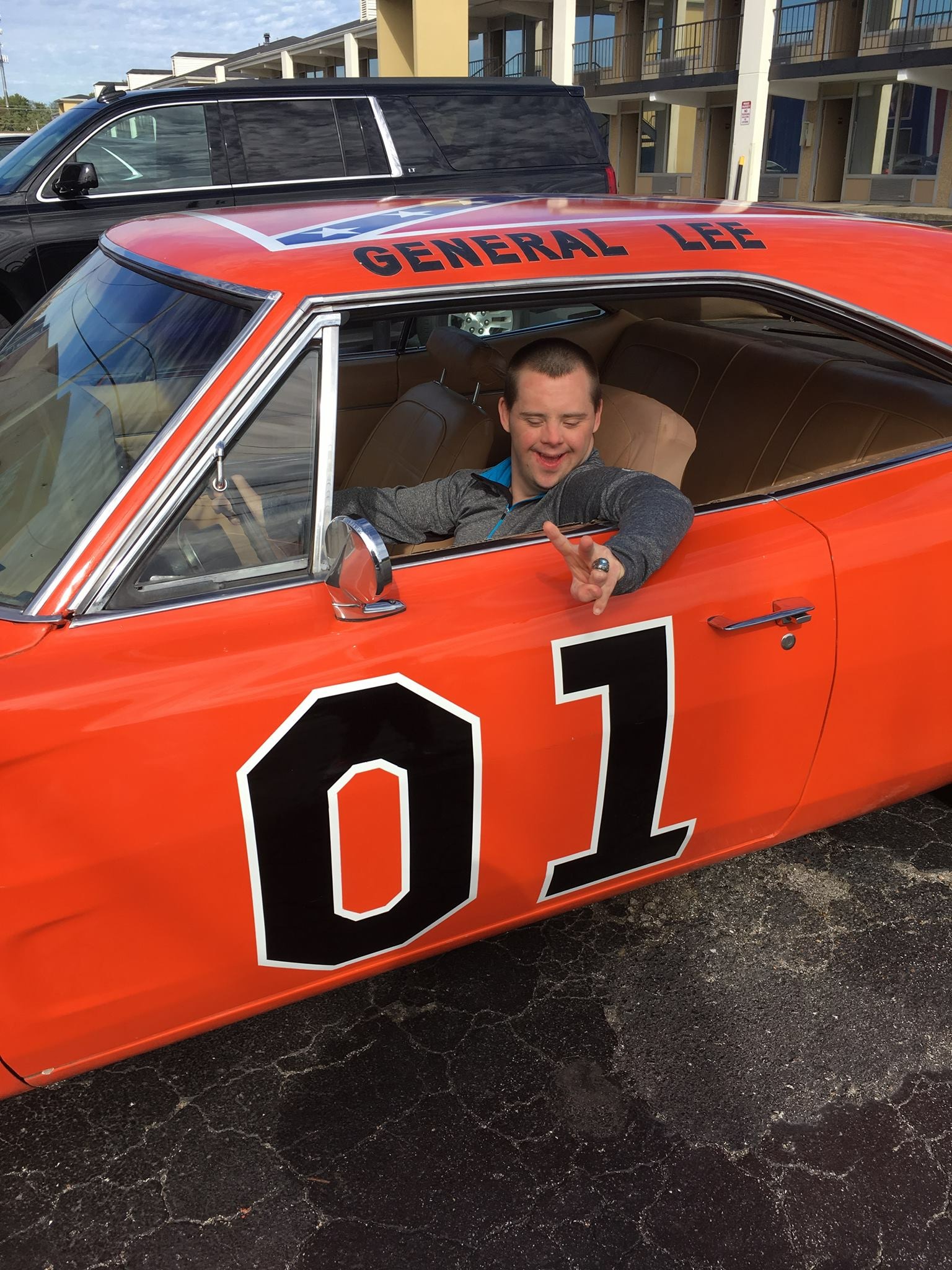 A white man sitting in an orange race car smiling