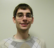 Jeremy faces the camera and smiles, against a beige-colored background.